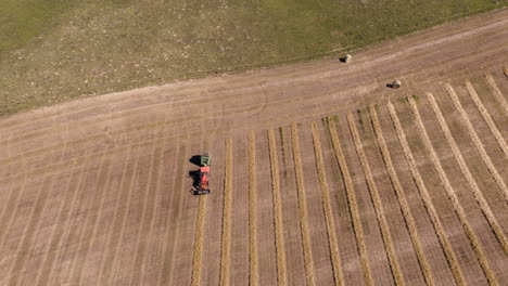 Top-down-Shot-Of-A-Farm-Machinery-Baling-A-Row-Of-Hay-At-The-Field-In-Saskatchewan,-Canada---aerial