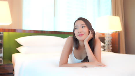 Eine-Asiatische-Frau,-Die-Bequem-Auf-Einem-Bett-In-Ihrem-Zimmer-Liegt-Und-Fernsieht,-Zeitlupe,-Gesichtsnahaufnahme