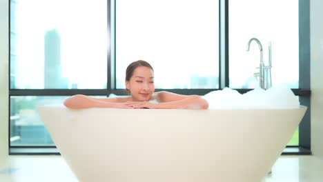 Close-up-on-an-Asian-woman-taking-bath-with-foam-on-the-top-floor-of-a-luxury-apartment