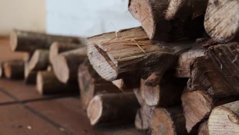 Closeup-firewood-logs-stacked-timber-woodpile-on-brown-tiles-floor-pull-back