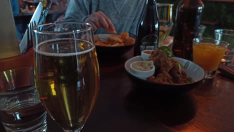 A-close-up-shot-of-a-glass-of-cider-with-a-woman-eating-food-in-the-background