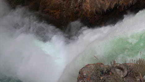 High-angle,-slow-motion-shot-of-Yellowstone's-Upper-Falls-with-mist-blowing-out-from-base-of-falls