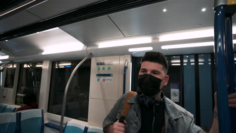 Man-Wearing-Face-Mask-While-Standing-Inside-The-Moving-Train-At-The-Underground-Metro-In-Montreal,-Quebec,-Canada
