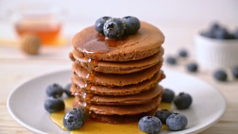 chocolate-pancake-stack-with-blueberry-and-honey-on-plate