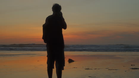 Silhouette-photographer-taking-photo-of-sunset-beach,-slow-reveal