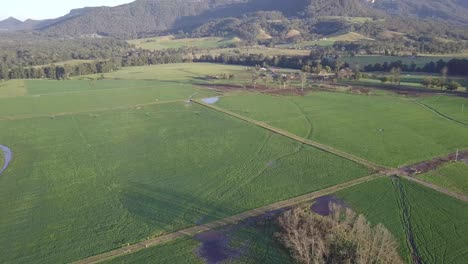 Flooded-crop-fields-in-Kangaroo-Valley-New-South-Wales-Australia,-Aerial-tilt-up-reveal-shot
