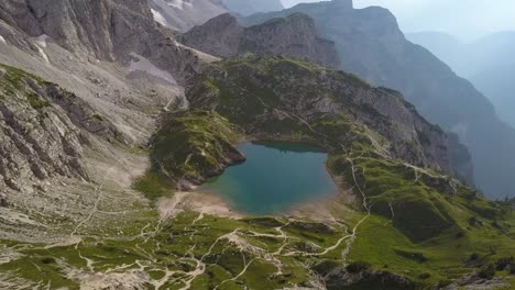 Aerial-of-a-Oasis-like-pond-in-the-mountains-in-Dolomites-in-Italy,-Lake-Coldai,-Alleghe,-Dolomites
