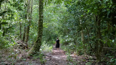 Slow-motion-shot-of-woman-walking-away-on-jungle-path-at-Asu-Island,-North-Sumatra,-Indonesia