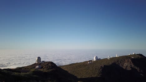 A-time-lapse-of-a-group-of-telescopes-in-a-mountain,-over-a-sea-of-clouds