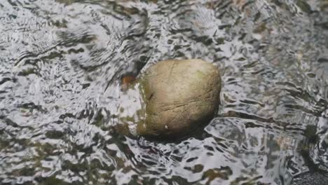 Clear-Water-Flowing-Through-A-Small-Rock-In-A-Stream-In-Kyoto,-Japan---Closeup-Shot