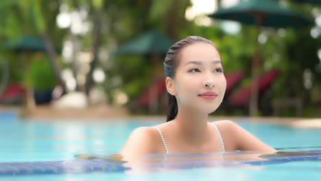 Face-Close-up-Asian-woman-in-water-up-to-her-neck-in-swimming-pool