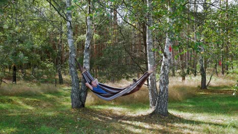 Man-relaxing-on-a-hammock-between-trees-in-the-Prądzonka-forest-Northern-Poland