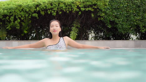 An-attractive-woman-lounges-in-the-shallow-water-of-a-resort-swimming-pool