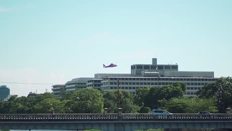 Ein-Roter-Rettungshubschrauber-Schwebt-über-Dem-Gebäude-In-Der-Innenstadt-Nahe-Der-Kamogawa-flussbrücke-In-Kyoto,-Japan