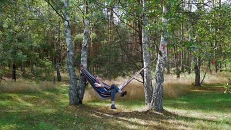 Man-Relaxing-In-A-Hammock-Between-Trees-In-Pradzonka,-Poland
