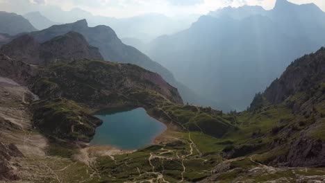 Beautiful-blue-pond-high-up-in-the-mountains-on-a-sunny-hazy-day-at-Lago-di-Coldai,-Alleghe,-Italy