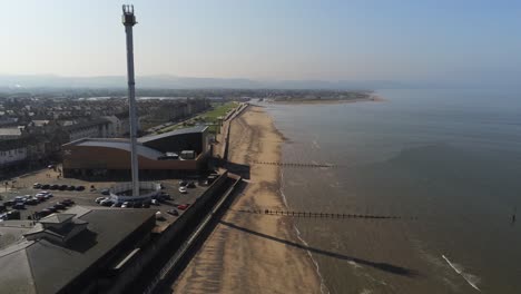 Popular-seaside-Rhyl-resort-town-aerial-rising-view-above-coastal-beach-sky-tower-attraction