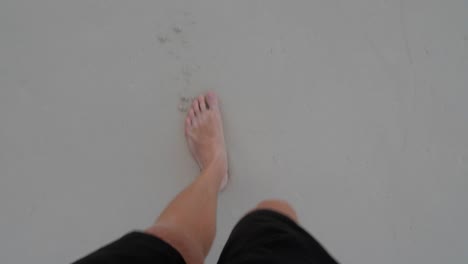Male-feet-walking-barefoot-on-sand-filmed-looking-down-from-the-man's-point-of-view