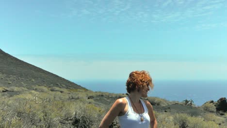 A-medium-shot-around-a-redhead-elegant-woman-in-a-volcaninc-island
