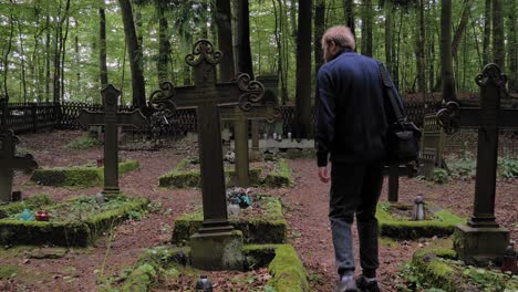 Man-Visiting-A-Grave-At-The-Cemetery-In-Pyszno,-Poland-Where-German-Foresters-Were-Buried-Before-World-War-II---full-shot