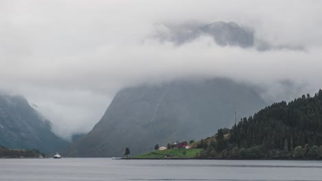 Hermoso-Lapso-De-Tiempo-En-Noruega-Sæbø,-Nubes-Pasando-Montañas,-Con-Una-Vista-Panorámica-Del-Océano-En-Primer-Plano,-Un-Pequeño-Bote-Pasando-A-Través-Del-Marco,-Alejándose-Lentamente