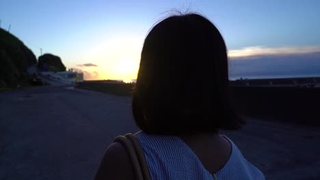 Camera-following-back-of-short-haired-female-walking-at-dusk-with-sunset-light-behind-her-SLOW-MOTION
