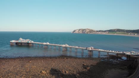 Full-length-shot-of-the-famous-Llandudno-Pier-with-the-Little-Orme-in-the-background,-Wales