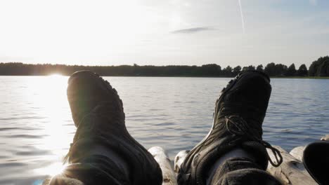 Man-Wearing-Black-Shoes-Lying-On-A-Wooden-Raft-By-The-Lake-In-Prądzonka,-Poland---Closeup-Shot