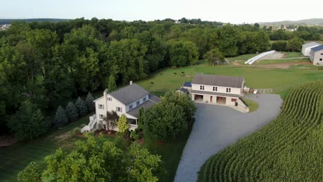 New-Amish-house-and-barn-in-Lancaster-County-Pennsylvania,-home-surrounded-by-farm-fields-and-meadow-pasture,-aerial-shot,-gray-two-story-home-with-shutters