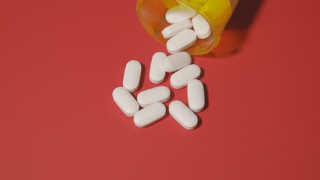 Píldoras-Blancas-Opioides-Derramadas-Sobre-La-Mesa-Para-La-Adicción-A-La-Salud-Medicina-Para-El-Dolor-Fondo-Rojo