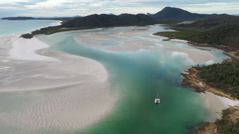 Wide-rising-drone-shot-of-Whitehaven-Beach-Whitsunday-Island-Australia-with-sailboat-in-water