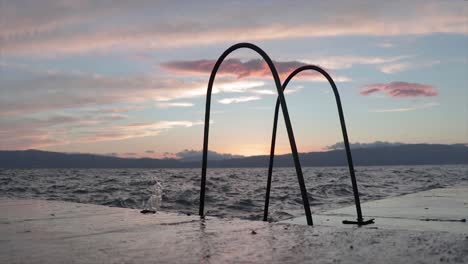 Wellen,-Die-Bei-Sonnenuntergang-Mit-Einer-Schönen-Goldenen-Stunde-Auf-Den-Pier-Eines-Natürlichen-Sees-Spritzen