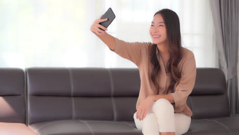 Feliz-Y-Atractiva-Mujer-Asiática-Haciendo-Videollamadas-Con-Su-Smartphone