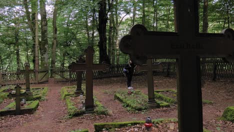 A-Female-Traveler-Visiting-The-Forest-Ranger-Cemetery-Nestled-In-Lush-Hill-Of-Pyszno,-Northern-Poland---Medium-Shot
