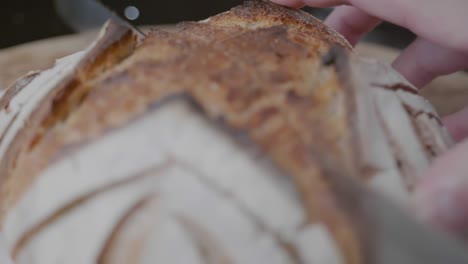 Close-up-Rack-Fokus-Eines-Messers,-Das-Durch-Einen-Laib-Handwerkliches-Brot-Schneidet