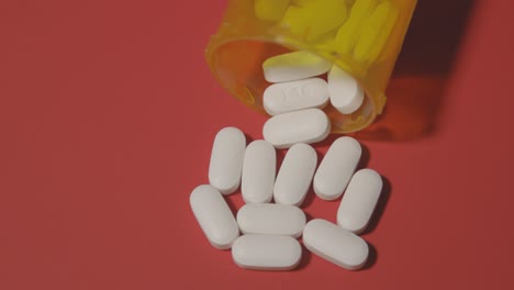 Píldoras-Blancas-De-Opioides-Derramadas-Sobre-Una-Mesa-Roja
