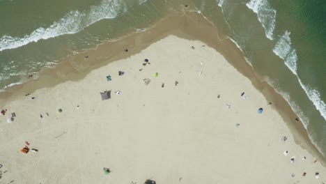 Bird's-eye-view-of-looking-down-on-a-beach-with-tourists-socially-distancing-while-on-vacation