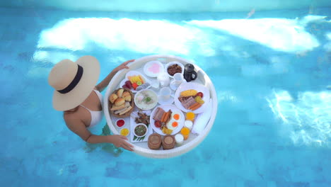Top-Down-View-of-Wealthy-Female-in-Swimming-Pool-With-Floating-Breakfast-Plate