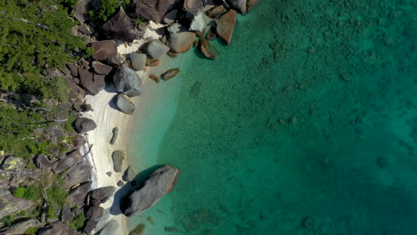 Downward-angle-lowering-drone-shot-of-beach-and-rocks-at-Hook-Island-near-Whitsunday-Australia