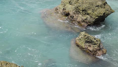 Slow-motion-shot-of-turquoise-water-surrounding-rocks-in-the-sea-at-Asu-Island,-North-Sumatra,-Indonesia