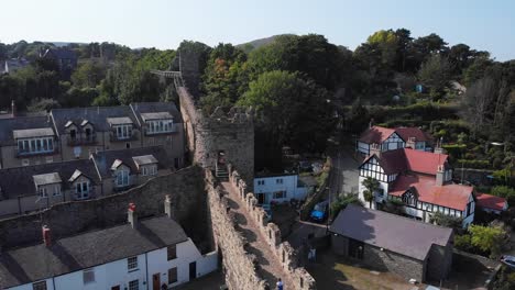People-walking-along-the-historic-stone-wall-of-Conwy-town-in-Wales,-aerial-view