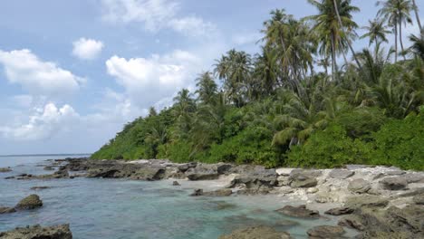 Ultra-slow-motion-shot-of-rocky-shore-with-palm-trees-and-clear-blue-water-at-Asu-Island,-North-Sumatra,-Indonesia---camera-pan-right