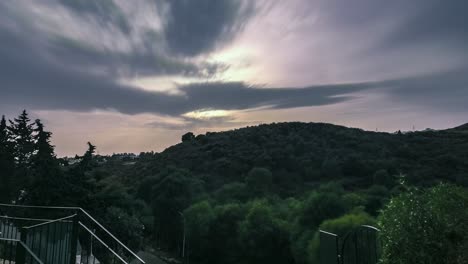 Time-lapse-during-sunset-behind-a-green-hill