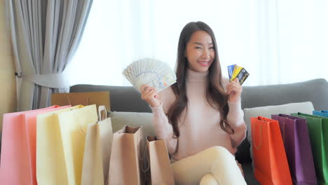 Begeisterte-Asiatische-Frau,-Die-Mit-Einem-Bargelddollargeld-Und-Kreditkarten-Vor-Der-Kamera-Posiert