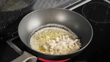 Close-up-of-a-frying-pan-while-cooking-onions-in-melted-butter