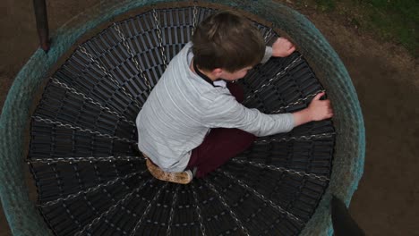top-down-above-young-boy-child-sitting-in-round-circular-park-swing