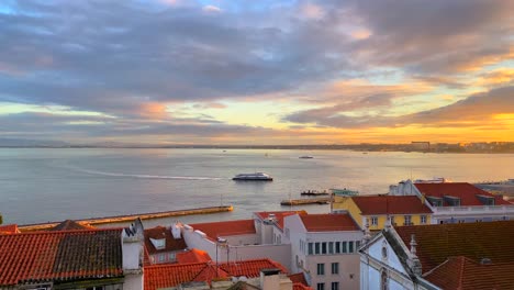 Wunderschöne-Aussicht-Auf-Den-Sonnenuntergang-Von-Einem-Fenster-Auf-Einem-Fluss-Mit-Fahrenden-Booten-Mit-Traditionellen-Orangefarbenen-Dächern-Und-Einem-Unglaublichen-Himmel-In-Der-Stadt-Lissabon,-Portugal,-4k-Statische-Aufnahme