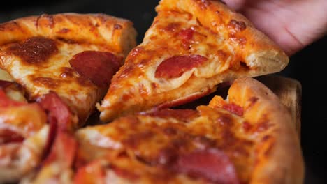 Close-up-of-a-hand-reaching-in-to-grab-a-mouth-watering-piece-of-pizza