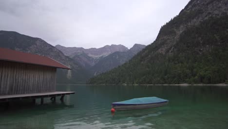 Lake-with-hut-and-boat-and-mountains-in-background
