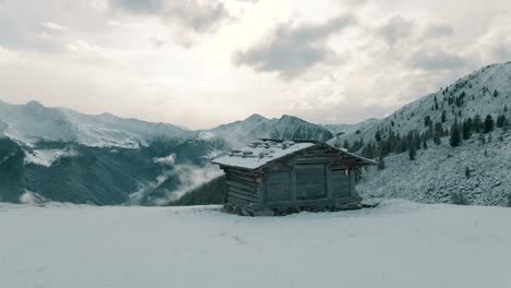 Alpine-hut-in-front-of-snow-covered-mountains-with-the-first-fresh-snow-of-the-season